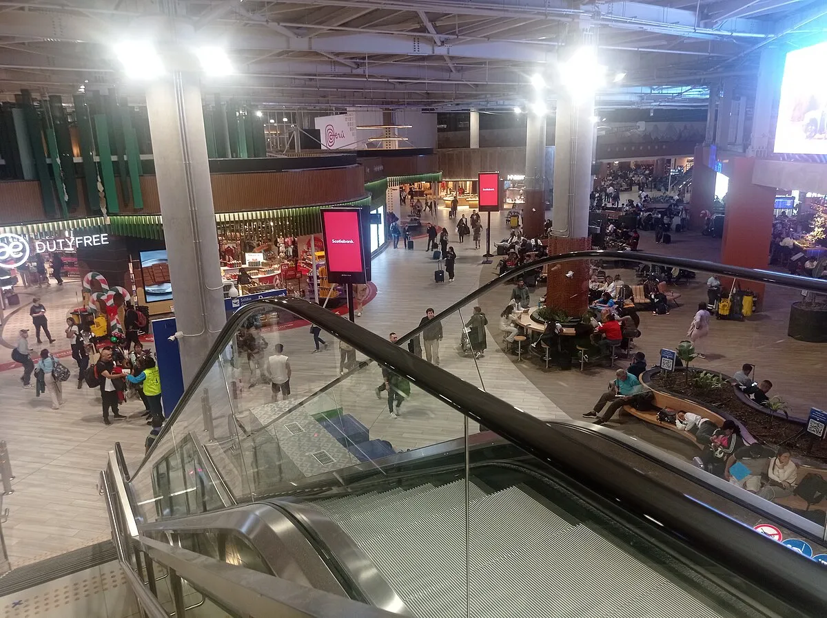 Hall con tiendas y escaleras eléctricas del nuevo terminal Jorge Chávez, donde recoge tu taxi aeropuerto Lima